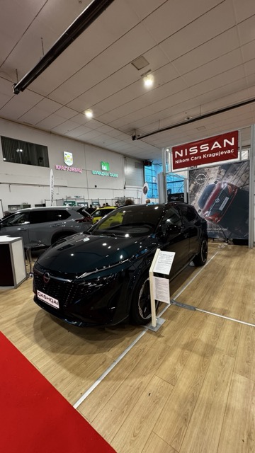 Soporte de tablet digital que muestra especificaciones de un coche en una feria del automóvil.